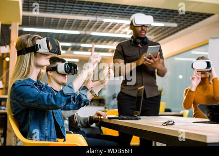 Group of positive colleagues testing virtual reality glasses. Handsome African businessman developing a project using virtual reality goggles Stock Photo