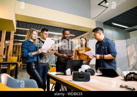 Young people software programmers testing a new apps with 3d virtual reality glasses, laptops and tablets in office Stock Photo