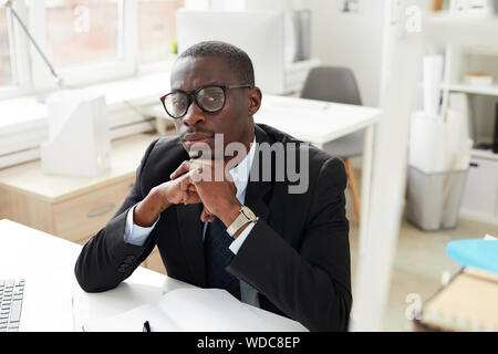 Portrait of African white collar worker in eyeglasses looking at camera while working at the office Stock Photo