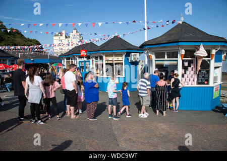 Holidaymakers queuing for ice creams and candy floss at a kiosk near the entrance to Llandudno pier, Llandudno, N.Wales Stock Photo