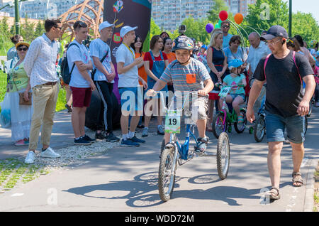 Russia, Kazan - May 31, 2019: A boy with Down Syndrome on a bicycle participates in a cycling race with his father on a sunny summer day. Charity bike Stock Photo
