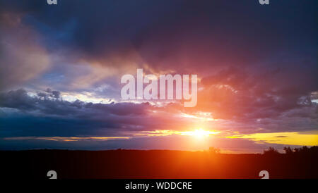 Bright and colorful, summer sunset on the background of cloudy, thunderclouds. Stock Photo