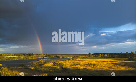 Rainbow after rain on the background of storm clouds. Stock Photo