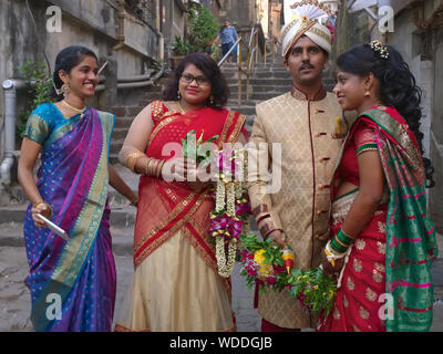 Holding a low-key wedding celebration in Mumbai, India, the festively dressed wedding couple (r) and friends step out into the couple's backyard Stock Photo