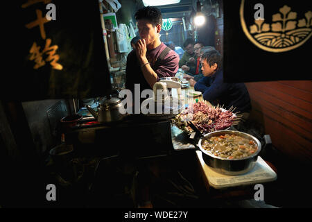 People waiting to eat grilled skewers of  chicken, pork and beef meat in a small shop at Omoide Yokocho alley. Stock Photo