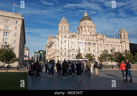 Tourists gather around the Beatles Statue at the Pier Head on Liverpool waterfront to take photographs. Stock Photo