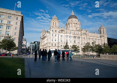 Tourists gather around the Beatles Statue at the Pier Head on Liverpool waterfront to take photographs. Stock Photo