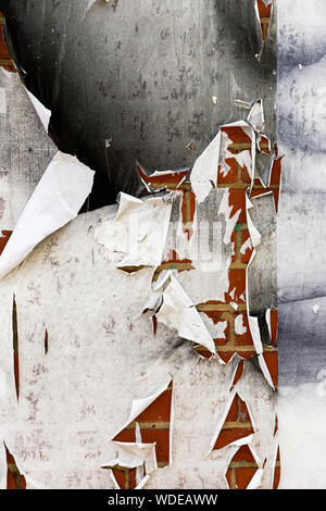 Ripped textured white paper posted on grungy brick wall surface. Stock Photo