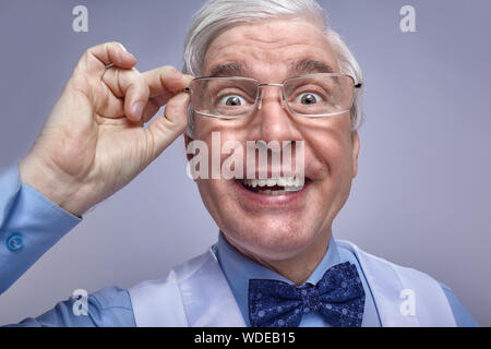 Close up portrait of funny smiling cheerful senior businessman clerk. Adult middle-aged man with glasses in hands with bulging eyes looking at the cam Stock Photo