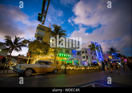 MIAMI - JANUARY 08, 2018: Neon lights decorate the Art Deco architecture behind a classic American car parked on Ocean Drive in South Beach. Stock Photo