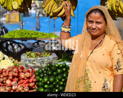 Indian Rajasthani market woman, clad in a beautiful sari, sells vegetable and bananas. Stock Photo