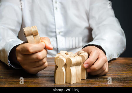 A man grabs a figurine of people from the crowd. Hiring employees. Market Segmentation and Niche Conquest. Human resources. Enticement of workers and Stock Photo