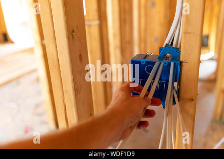 Hand working on electrical wires in new home construction Stock Photo