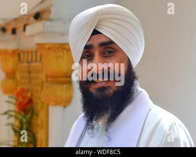 Middle-aged Thai Sikh man with white turban smiles for the camera. Stock Photo