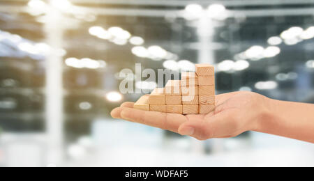 Wood block stacking as step stair with arrow up in a hand. Ladder career path concept for business growth success process Stock Photo