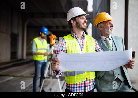 Engineer, foreman and worker discussing in building construction site Stock Photo