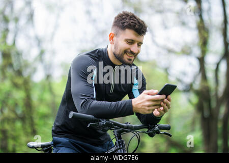 Bottom and side view of bicyclist on bike using navigator on smart phone, explore map and search GPS coordinates while biking in mountains. Stock Photo