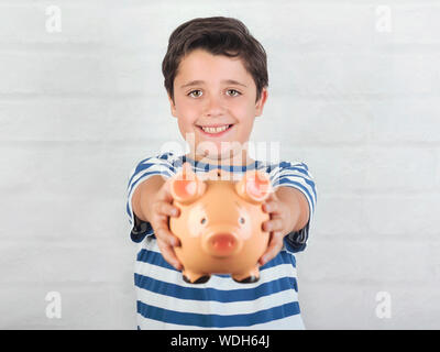 funny child with piggy bank on brick background Stock Photo