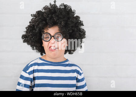 funny child making a grimace wearing nerd glasses on brick background Stock Photo