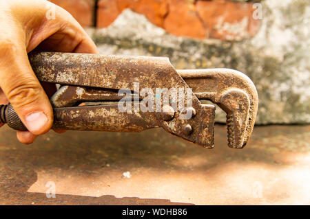 Old adjustable wrench in the plumbing hand - a working tool. Background. Stock Photo