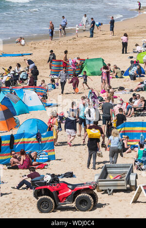 Holidaymakers on a staycation holiday enjoying themselves on Fistral Beach in Newquay in Cornwall.