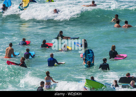 Holidaymakers on a staycation holiday enjoying themselves in the sea at Fistral in Newquay in Cornwall.