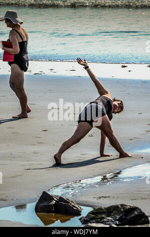Two woman are out on the beach for their morning exercise, in two different ways. It is a lot of  fun to do on vacation , but forgotten at home. Stock Photo