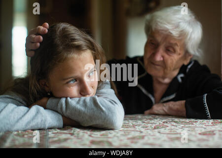 Elderly woman comforts running his hand a weeping beloved granddaughter. Stock Photo
