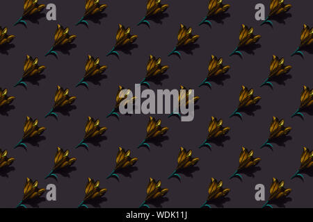 Pattern of golden lilies on dark background trend flat lay concept with fashionable toning. Many flowers pattern Stock Photo