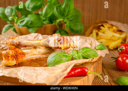 food leftovers from grilled chicken and chilli with tomato, fries and basil on wooden background Stock Photo