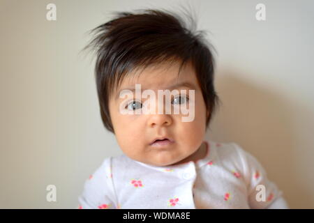 Six Months Old Baby Girl With Long Hair Looking Down With Mouth