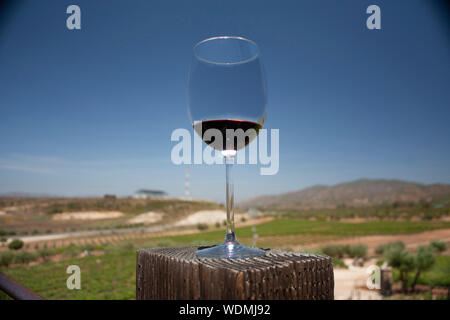 Glass served with red wine in mountainous landscape of vinicultural fields in Baja California Mexico Stock Photo