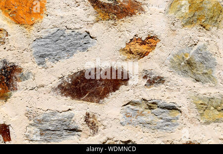 Concrete wall made of multicolored stones, exterior background texture. Colorful stoned wall. Stock Photo