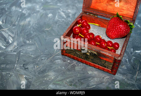 Assorted mix of organic red fresh berries, close up, front view in wooden box. Strawberry and red currant on grey background with copy space. Unique Stock Photo