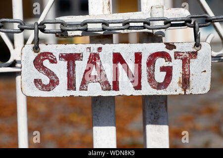 Sign written in Swedish language attached to a gate displays closed. Stock Photo