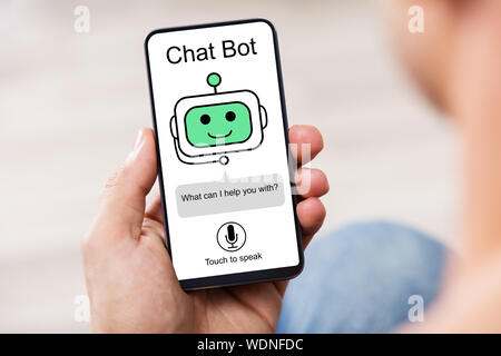 Close-up Of Man Using Chat Bot Application For Chatting On Smartphone Stock Photo