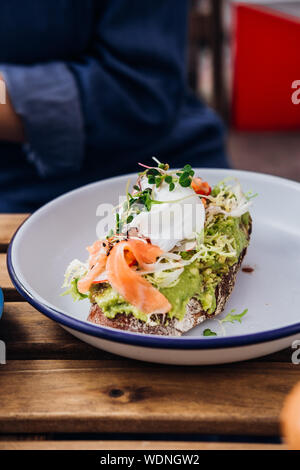 Avocado toast with smoked salmon and poached egg at hipster coffee shop Stock Photo