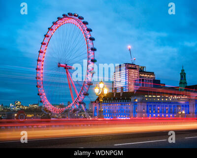 View of the famous London Eye from Westminster Abbey bridge with red car traces in composition - England, UK Stock Photo
