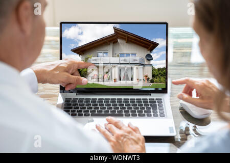 Rear View Of Two Businesspeople Looking At House On Laptop Stock Photo