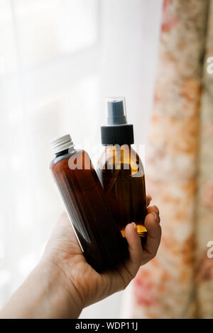 Woman's hands holding two glass brown bottles with spa cosmetics. Beauty blogging, salon therapy