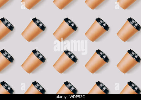Seamless pattern of many coffee to go paper cups on grey background. Open composition. Flat lay style. Stock Photo