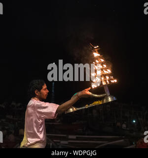 Indian Hindu priest holding candles during the Ganga Aati ritual at the Dashashwamedh Ghat in Varanasi, Uttar Pradesh, India, Asia Stock Photo