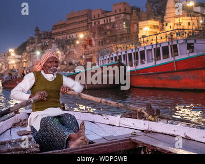 Indian man rowing boat down the Ganges River at dawn in Varanasi, Uttar Pradesh, India, Asia Stock Photo