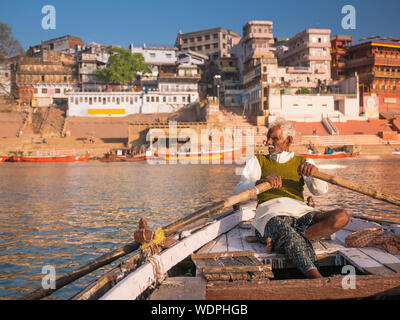 Indian man rowing boat down the Ganges River in Varanasi, Uttar Pradesh, India, Asia Stock Photo