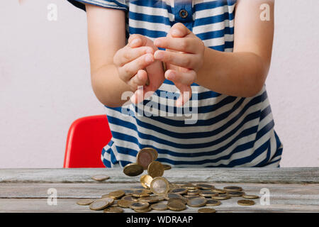 Midsection Of Boy Dropping Coins On Wooden Table