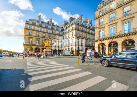 A gilded bronze equestrian statue of Joan of Arc by Emmanuel Frémiet in the Place des Pyramides in Paris France as tourists walk on the street Stock Photo