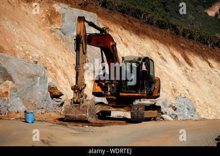 Excavator working on the excavation works of a road, moving rock and earth Stock Photo