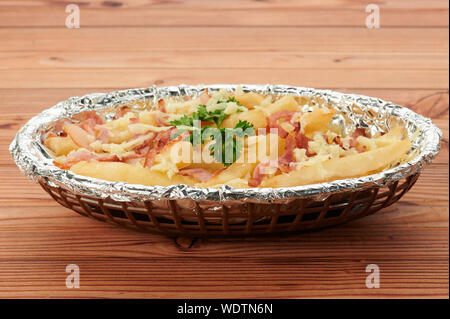 Tasty fried fries with cheese on top in wooden table Stock Photo