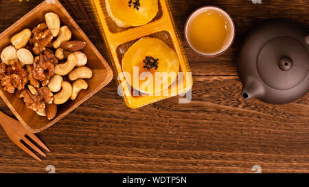 Moon cakes with tea on dark wooden table, holiday concept of Mid-Autumn festival traditional food layout design, top view, flat lay, copy space. Stock Photo