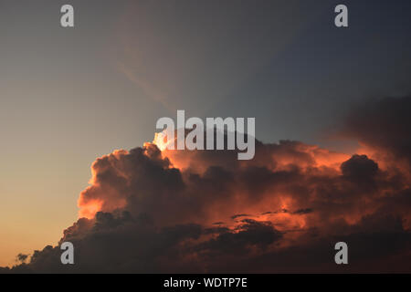 Cumulonimbus cloud formations on tropical sky with horizon is turning yellow at sunset, Purple and orange color clouds hunk at night , Thailand Stock Photo